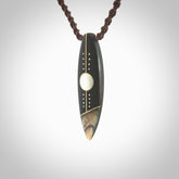 This photo shows a medium sized surfboard pendant hand carved from Lignum Vitae wood with Mother of Pearl and Paua Shell inlay, alongside; brass and silver. This is a stand out one off necklace for those who appreciate art to wear. It is provided with a cord in brown that is a fixed length with Paua Shell Toggle. We ship this piece worldwide and shipping is included in the price.